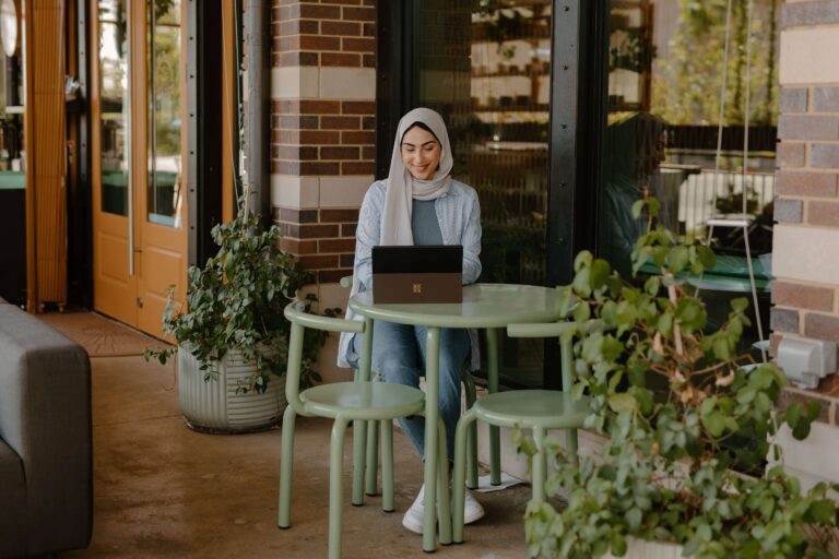 A woman working outside a coffee shop using a Microsoft Surface laptop
