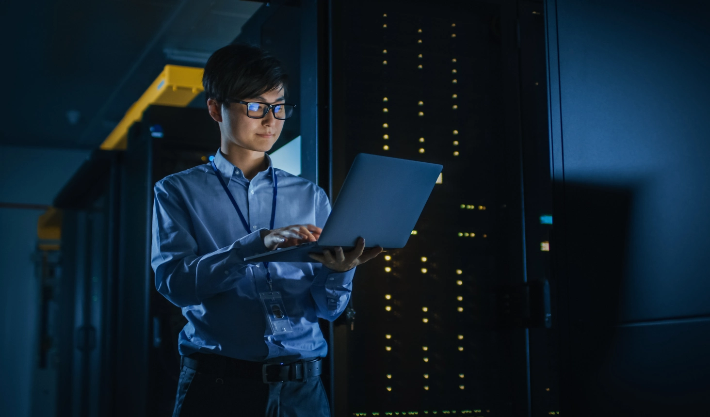 person holding laptop standing beside servers